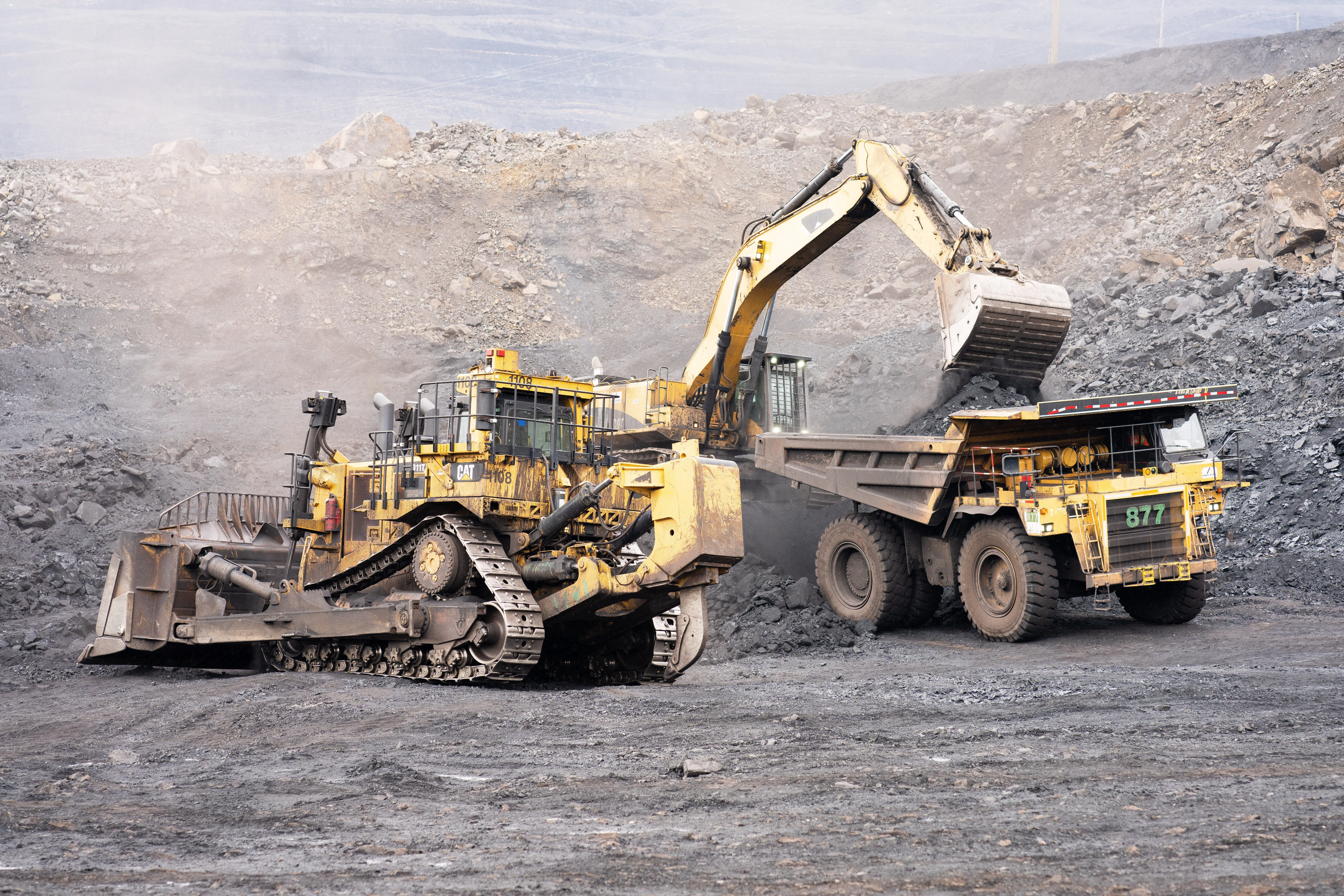 Dozer and excavator loading a haul truck on an active mine bench
