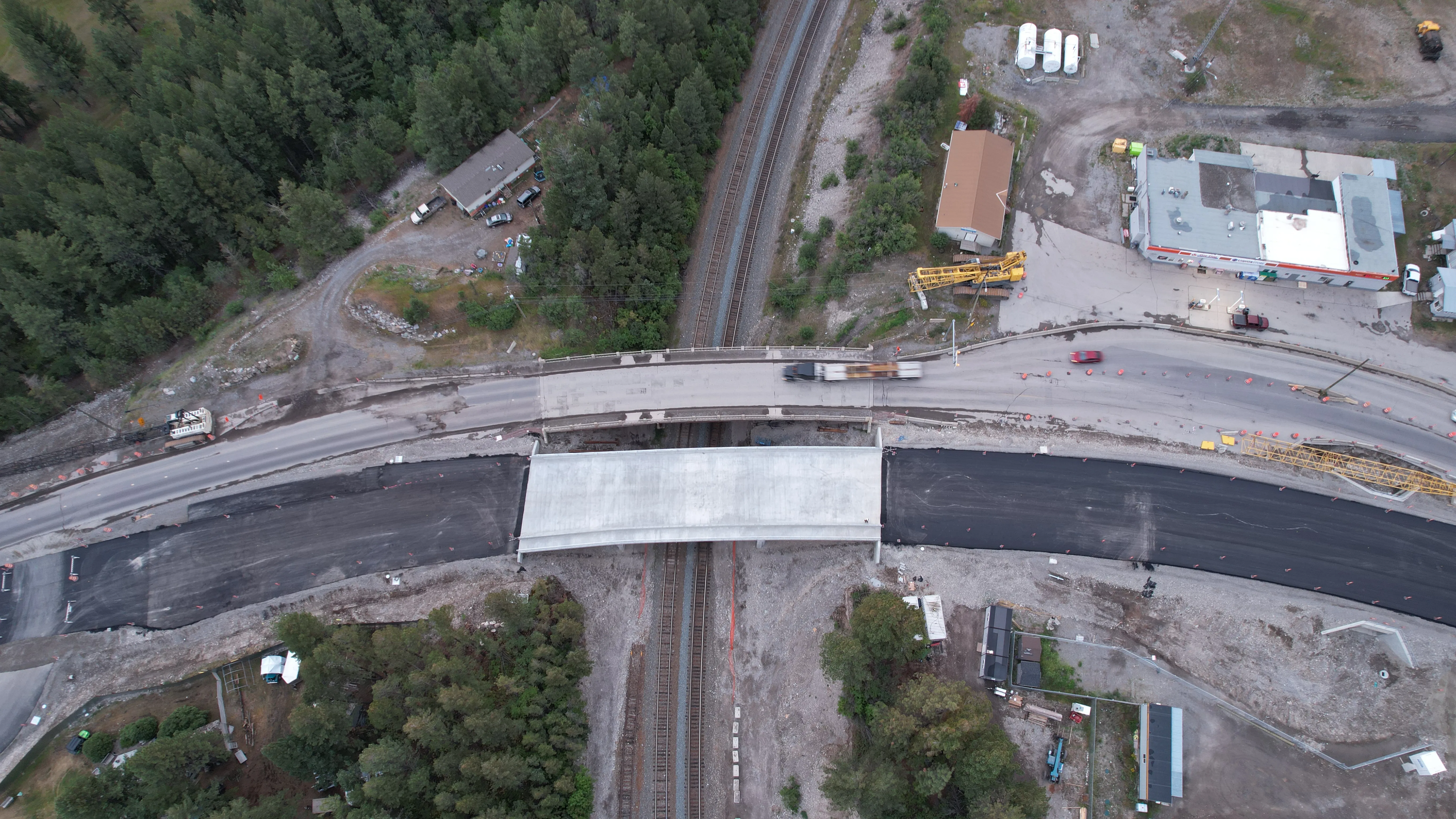 Aerial view of a new highway overpass and fresh asphalt alignment beside the rail line