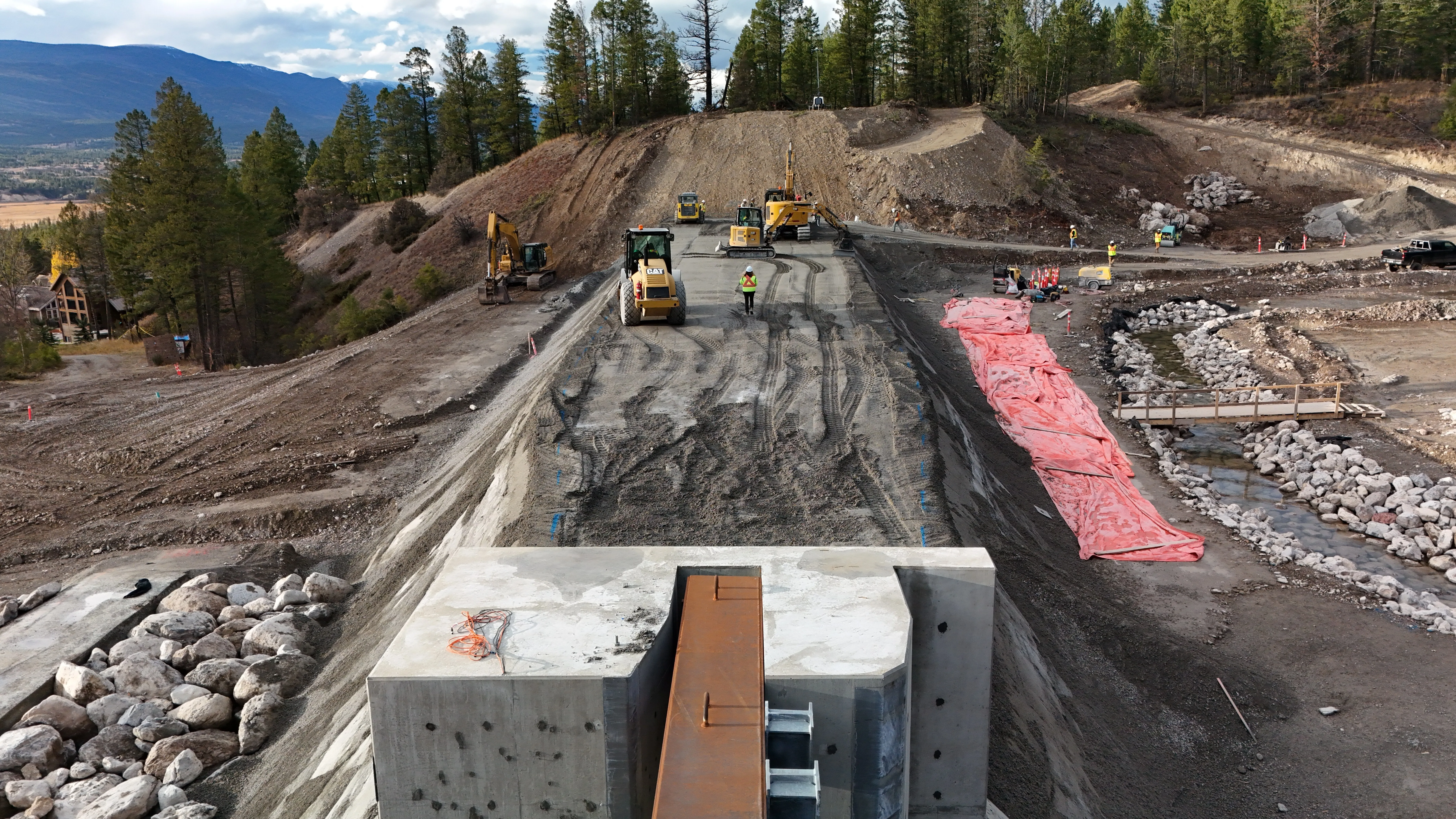 Crews compacting the crest of an avalanche berm above a valley