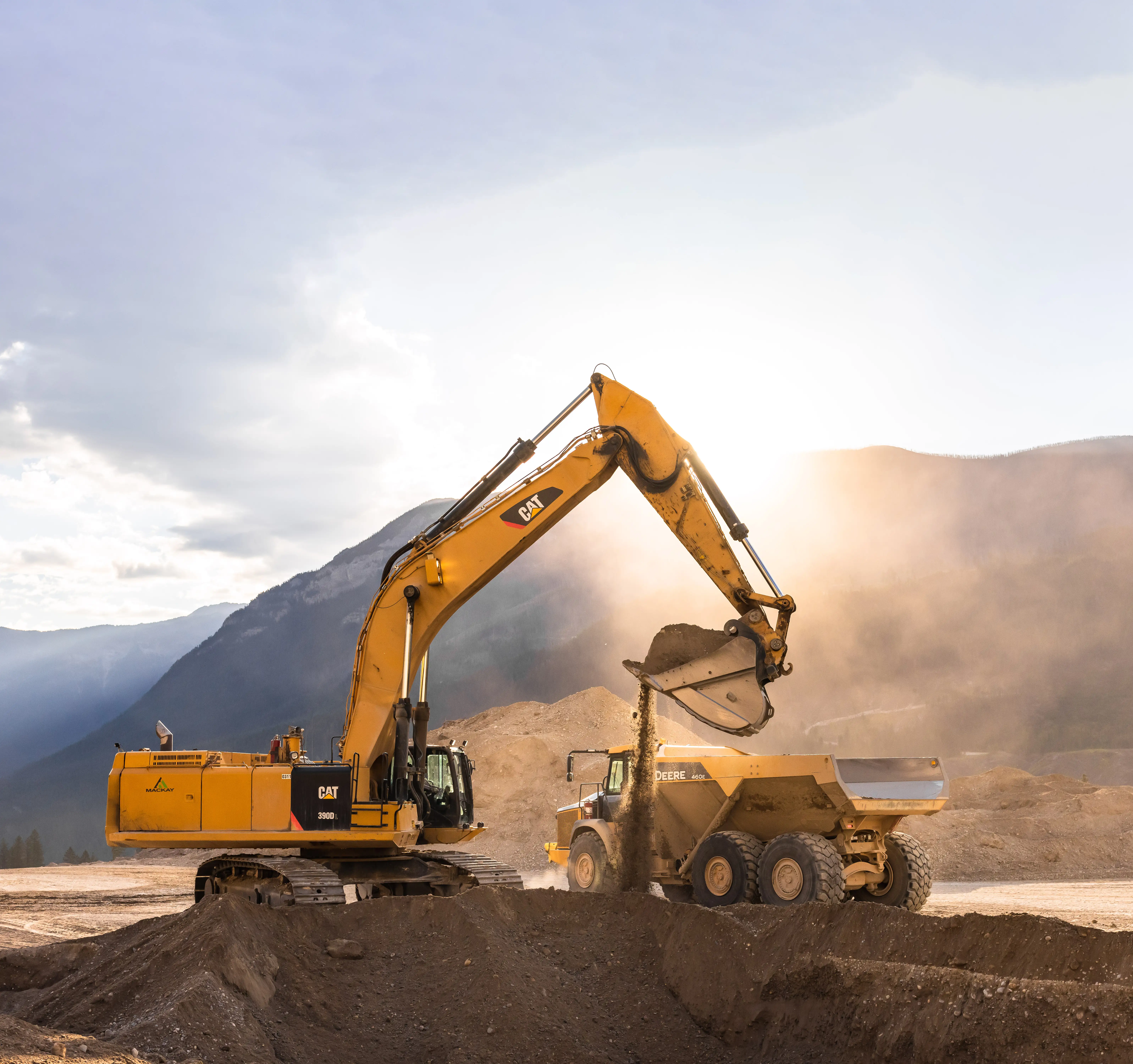 Mackay excavator loading a rock truck in golden-hour dust
