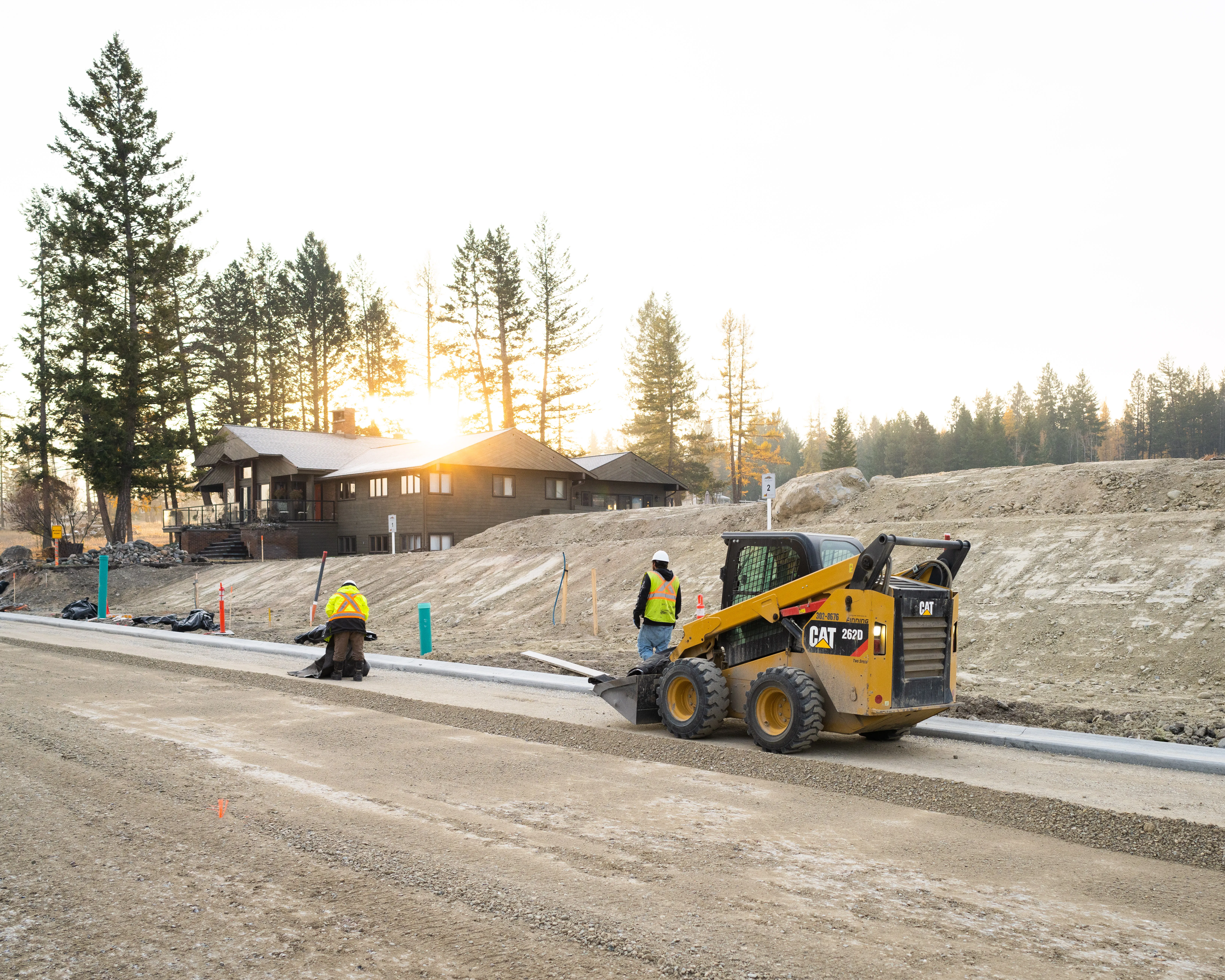 Crew placing curb and grading a rebuilt residential street at sunrise